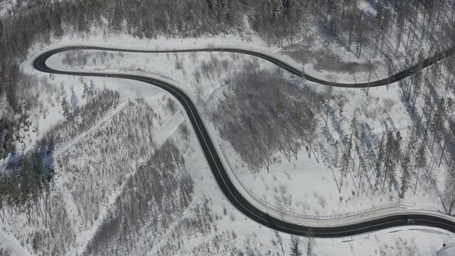 Curvy windy road in snow covered forest, top down aerial view. Winter landscape. DJI Mavic 2 Pro 4k dlog-m ungraded flat.