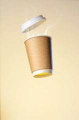 Levitating paper cup with evaporation from a hot coffee. Clubs of steam from a hot drink. Paper Cup Layout For Advertising. Paper cup of coffee with a plastic cap levitates in the air