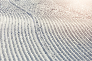 Fototapeta na wymiar Close-up ski piste, ski slope, Abstract background with tracks on the snow, newly groomed snow