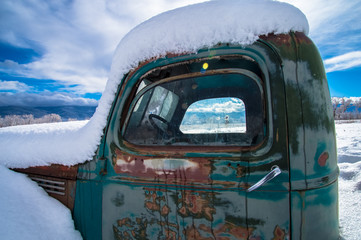 Window with a Mountain View through Snow Frosted, Rusted Vintage Truck 