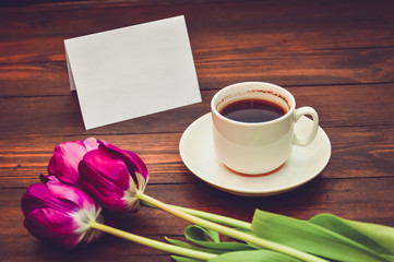 cup of coffee with flowers and a card for inscriptions on a wooden background