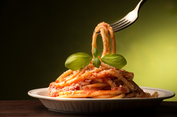 dish with spaghetti and tomato sauce on the wooden table