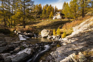 typical mountain hut on the river in the Alps on the Simplonpass - obrazy, fototapety, plakaty