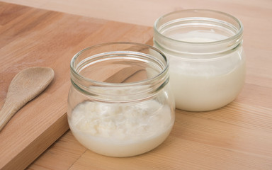 Obraz na płótnie Canvas Organic Kefir and kefir grains in glass jars with wooden board and spoon