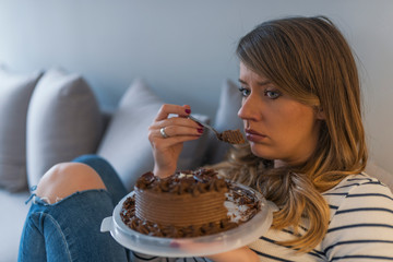 Depressed woman eats cake. Close up of woman eating chocolate cake.