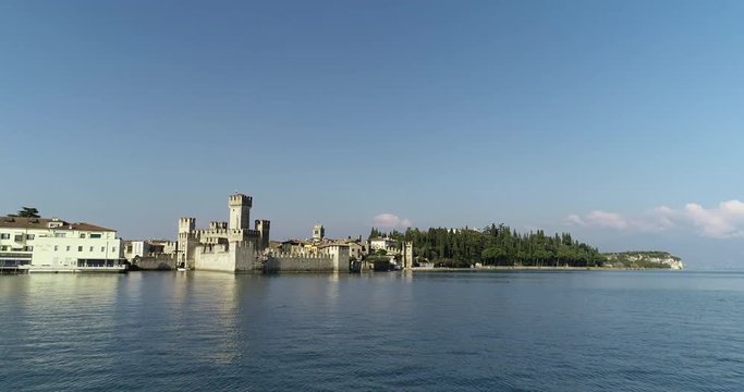 Drone shot over the water of the Beautiful Sirmione Castel in Garda Lake - Italy.