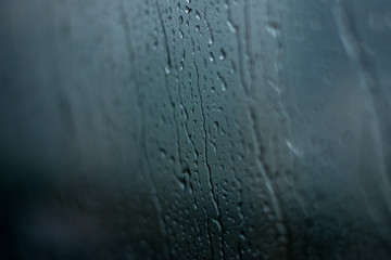 Blured rain drops on the window on the dark background.