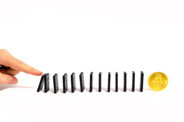 Human hand pushing dominoes on the bitcoin on a white background.