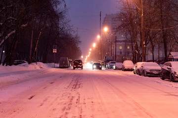 city road covered with snow with cars on the sidelines in winter season b