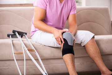 Young man with injured knee recovering at home