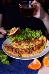 Woman is eating a piece of omelette with a fork. Breakfast meal