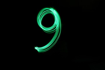 Long exposure, light painting photography.  Single number nine in a vibrant neon green colour against a black background
