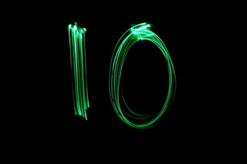 Long exposure, light painting photography.  Double digit ten in a vibrant neon green colour against...
