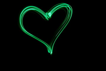 Long exposure, light painting photography.  Vibrant neon green heart symbol shape, love and romance...