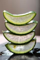Aloe vera slices stacked on dark board. Gel inside aloe leaf. Health and beauty concept.