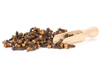 Lot of whole small dried cloves spice heap with wooden scoop isolated on white background