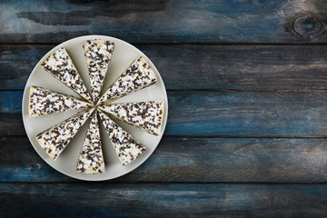 Cheesecake with chocolate chips on a white dish, on a beautiful wooden background. Top view, with the copy space for your text.