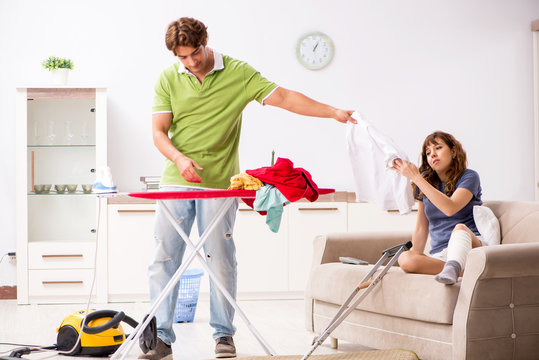Husband helping leg injured wife in housework 