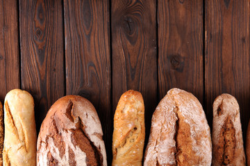 Assortment of baked bread and bread rolls on wooden table background