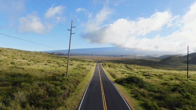 Aerial drone footage of Hawaii State Route 200, also called Saddle Road, between the volcanic mountains Mauna Kea and Mauna Loa on the Big Island of Hawaii, USA. Cinematic panning through landscape.