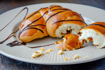 Fresh croissant with black chocolate on a white plate