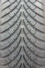 Close-up winter tire tread. Textured tire tread. Part of brand new modern winter car tire. vertical...