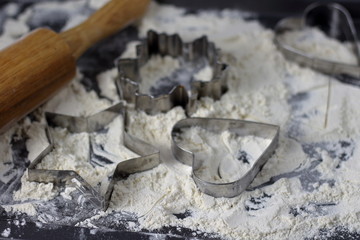 Cookie cutter in shape of star, heart, leaf, on a baking sheet with flour and rolling pin in the process of baking cooking, baking tools