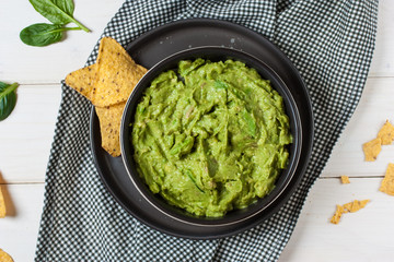 Homemade guacamole with corn chips top view on rustic wooden table 