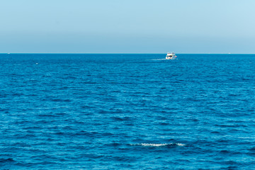 Obraz premium Tourist ship sailing in ocean. shipping business tourism concept. Background. Blue sea, pink sky at dawn and a white ship on the horizon. Concept of rest, vacation, weekend and cruise.