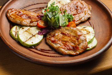 Grilled chicken breast with vegetables on clay plate.