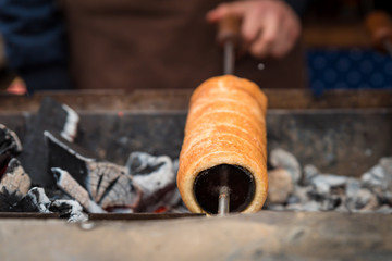 delicious chimney cake on a wooden mold is baked on the grill