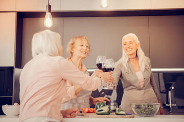 Joyful happy aged women cheering with glasses of wine
