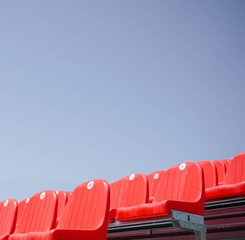row of red chairs on background of blue sky