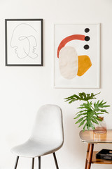 Stylish vintage interior of living room with design chair, retro table with tropical leafs in vase...