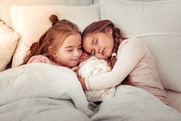 Beautiful cute sisters sleeping on the bed