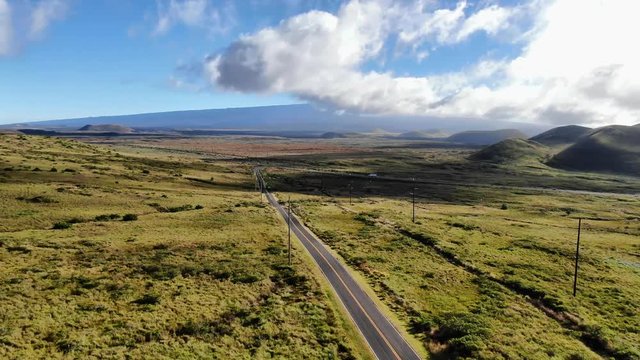 Aerial drone footage of Hawaii State Route 200, also called Saddle Road, between the volcanic mountains Mauna Kea and Mauna Loa on the Big Island of Hawaii, USA. Cinematic panning through landscape.
