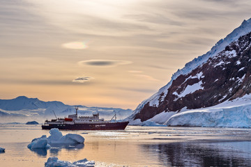 Touristic antarctic cruise vessel among the icebergs with glacie