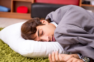 Young employee sleeping on the floor at office 