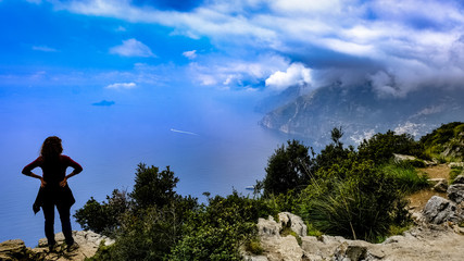 Naklejka na ściany i meble A woman from the back watching the magnificent view at God's Path trail above Amalfi coastline, Italy.