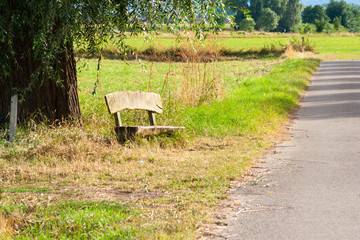 Old wooden bench next to a dirt road in the countryside