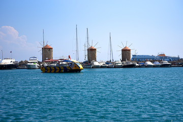Fototapeta premium The windmills,fort of St Nikolas,Church of the Assumption and the Governors palace are on Rhodes Mandraki Harbour 