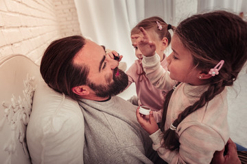 Cheerful happy girls playing with their father