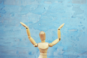 Wooden model showing dramatical pose in front of blue art background