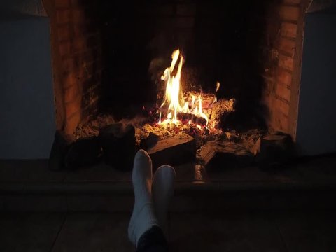 slow motion of a fireplace and feet with white socks enjoying the heat