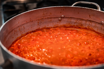 Traditional famous Italian tomato sauce for any kind of pasta, local name for this dish is "sugo". Slow flame cooking, rich red bubbles in steel kitchen. Mediterranean style and nutrition habits. 