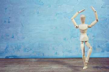 Wooden model showing dramatical pose in front of blue art background