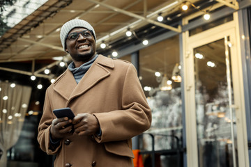 Fototapeta na wymiar Cheerful handsome African-American man standing outside restaurant