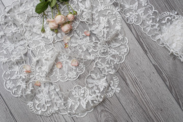 White wooden background with white spring flowers roses and lace ribbon. Happy womans day. The...