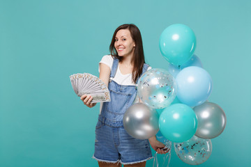 Pretty young woman hold fan of money in dollar banknotes cash money, celebrating with colorful air...