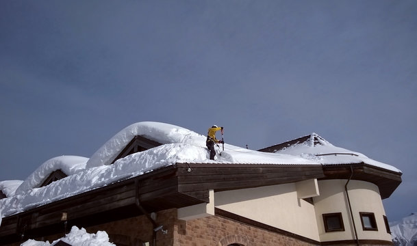 Worker removes snow from the roof at Rosa Khutor 01/24/2019